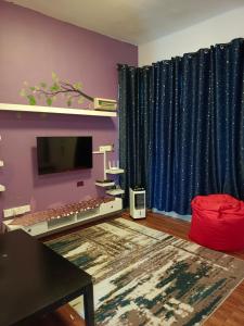 居銮HOMESTAY D'TEPIAN CASA, BANDAR SERI IMPIAN KLUANG的客厅配有电视和蓝色窗帘