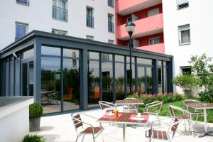 里昂里昂市奥德利生物园公寓式酒店的一座带桌椅的建筑的玻璃延伸部分