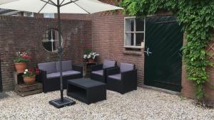 CothenBoerengastenverblijf De Kromme Rijn的一座带椅子和遮阳伞的庭院位于大楼旁