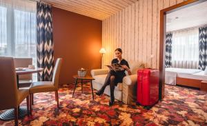 莫雄马扎尔古堡拉奇特公园酒店的坐在酒店房间沙发上的女士,带行李箱