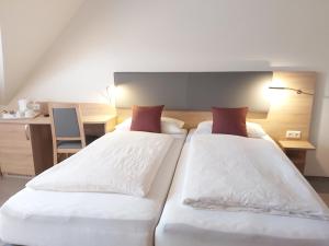 布里特林根Pension Heuer的一间卧室配有两张带白色床单和红色枕头的床。