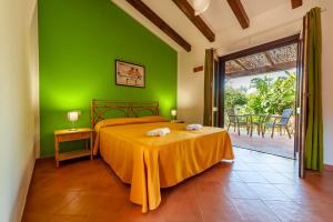 卡梅罗塔码头幸福村酒店的一间卧室设有绿色的墙壁、一张床和一张桌子