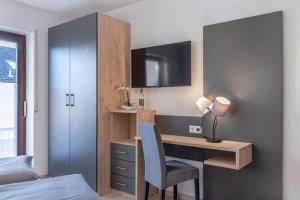 腓特烈港Comfort Apartment Buchhorn的一间卧室配有书桌、一张床、一张桌子和椅子