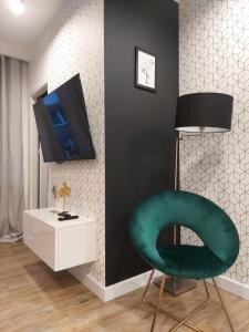 琴斯托霍瓦Apartament Premium的客厅配有绿色椅子和电视