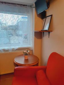 格但斯克Pokoje Gościnne的一间设有红色沙发、桌子和窗户的客房