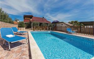 瓦图拉Stunning Home In Valtura With 4 Bedrooms, Wifi And Outdoor Swimming Pool的一个带两把蓝色椅子的游泳池,围栏旁