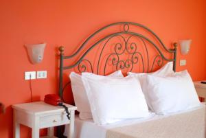 拉齐塞Hotel Benacus的橙色卧室配有带白色枕头的床和红色电话