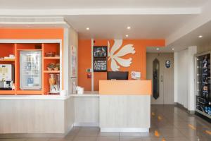 Isle-AumontPremiere Classe Troyes Sud - Parc St Thibault的餐厅拥有橙色的墙壁和柜台