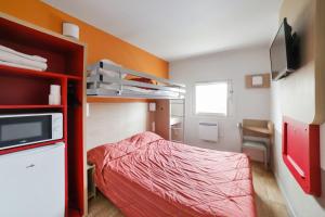 萨塞勒Premiere Classe Paris Nord - Sarcelles的小房间设有床铺和电视