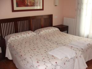 圣胡安德奥尔特加Alojamiento Rural La Henera的一间卧室配有白色床单和红色鲜花。