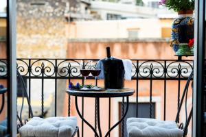陶尔米纳瓦伦蒂娜旅馆的阳台上的桌子上摆放着一瓶葡萄酒和玻璃杯