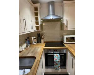 里彭Swallow Cottage的厨房配有白色橱柜和炉灶烤箱。