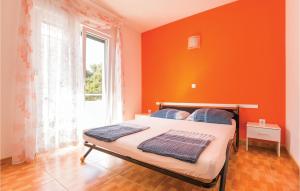 马卡尔斯卡Cozy Apartment In Makarska With Kitchen的一间卧室设有橙色的墙壁和一张带窗户的床
