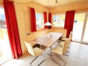 上陶恩Nice chalet in Hohentauern Styria with sauna的一间用餐室,配有红色窗帘和一张木桌及椅子
