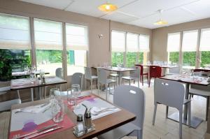 苏瓦松Kyriad Direct Soissons的用餐室设有桌椅和窗户。