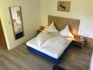 莱希河畔魏森巴赫佛罗伦萨自然公园酒店的一间卧室配有一张带白色床单和镜子的床