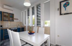 扎达尔Beautiful Apartment In Zadar With Outdoor Swimming Pool的厨房配有白色的桌子和白色的椅子