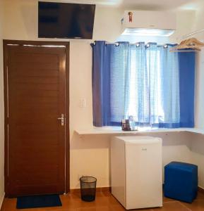 佩鲁伊比Pousada Peruibe 455的一间设有门的房间和一个带蓝色窗帘的窗户