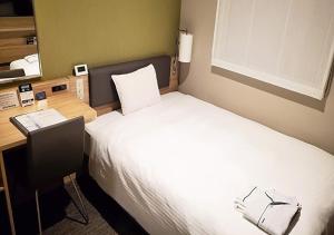 东京KEIKYU EX INN Haneda的酒店客房配有一张床、一张书桌和一台笔记本电脑