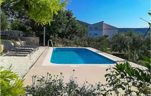维尼斯切Awesome Home In Vinisce With Outdoor Swimming Pool的庭院内的游泳池,带椅子和树木