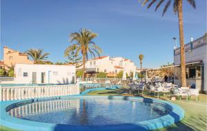 托雷维耶哈Amazing Home In Torrevieja With 3 Bedrooms, Wifi And Outdoor Swimming Pool的棕榈树和椅子的度假村内的游泳池