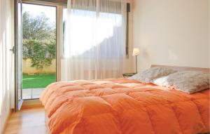 利亚内斯Beautiful Apartment In Llanes With Kitchen的一张橙色的床,位于一个设有大窗户的房间