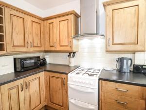 科尔温湾The Nook 285B的厨房配有木制橱柜和白色炉灶烤箱。