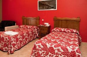 Alcaracejos米格尔​​安赫尔乡村酒店的一间卧室设有两张床和红色的墙壁
