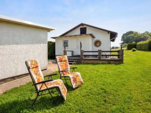 MosbachHoliday home in Thuringia with garden的坐在房子前面的草上,有三把椅子