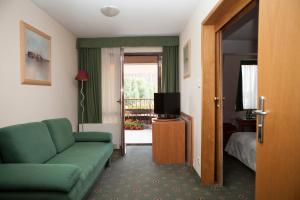 克拉科夫瑟斯亚酒店的客厅配有绿色沙发和电视