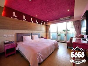 高雄R8环保商旅的一间卧室设有一张粉红色天花板的大床