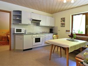 Hofstetten萨尔蒙斯巴赫2号公寓的厨房配有白色橱柜、桌子和桌子。