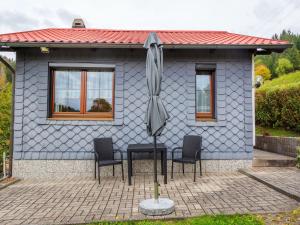 LangenbachHoliday home in Thuringia near the lake的蓝色房子,带三把椅子和一把伞