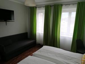 斯皮茨Gästehaus Ruinenblick的一间卧室配有绿色窗帘、一张床和一张沙发