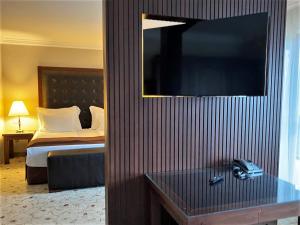 韦林格勒Maxi Park Hotel & Spa的酒店客房,设有床铺和墙上的电视