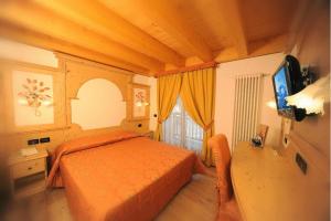 科姆梅扎杜拉嘉尼伊尔吉里欧酒店的一间卧室配有橙色的床和电视