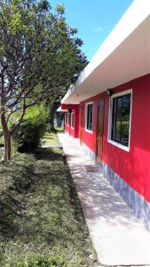巴尼奥斯La Estancia de Runtún Km 7的树旁有人行道的红色建筑
