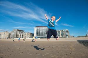 奥斯坦德奥斯坦德瓦亚木多酒店的一名在海滩上跳上空中的男孩