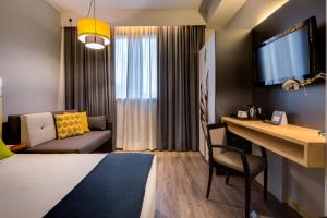 博洛尼亚Holiday Inn Bologna - Fiera, an IHG Hotel的客房设有床、书桌和沙发。