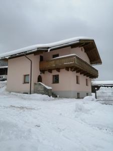 迈斯霍芬Grünwald Chalet的雪覆盖的房子,设有阳台