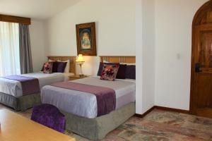 乔卢拉Santo Refugio Heritage Hotel的酒店客房设有两张床和一张桌子。