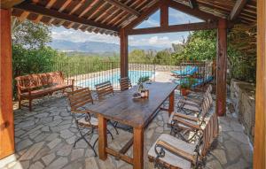 索塔Amazing Home In Sotta With House A Mountain View的一个带游泳池的庭院里的一张木桌和椅子