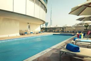 迪拜卡尔顿市中心酒店（原迪拜华威酒店）的一座大楼内的游泳池,配有椅子和遮阳伞