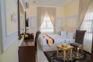 苏尔Arkan Al Barzah Hotel Apartment的一间卧室配有一张床、一把椅子和一张桌子