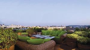 耶路撒冷Mamilla Hotel的一个带绿色家具和一张桌子的庭院