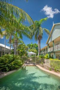 麦凯新乐花园汽车旅馆的棕榈树建筑前的游泳池