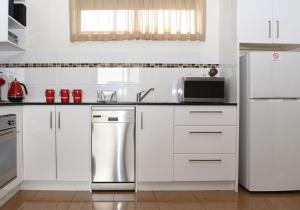 德罗马纳Dromana Beach Getaway的厨房配有白色橱柜和不锈钢冰箱