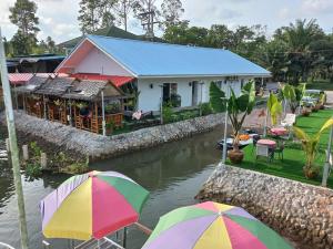 素叻Boat house marina restaraunt and homestay的河前有雨伞的房子