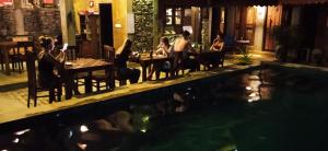 尼甘布Negombo The Nature Villa and Cabanas的一群人坐在游泳池旁的桌子旁