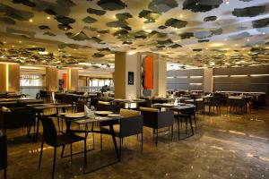 吉赞Grand Plaza Hotel - Jazan的餐厅设有桌椅和带鱼天花板的天花板。